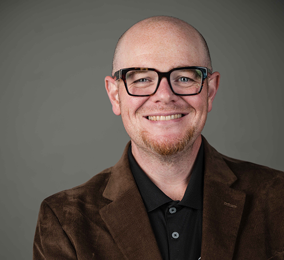 Jordy Jones pose avec son ordinateur portable et son fils sur les genoux.